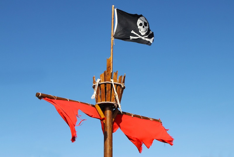 Foto van een scheepsmast met piratenvlag en kraaiennest