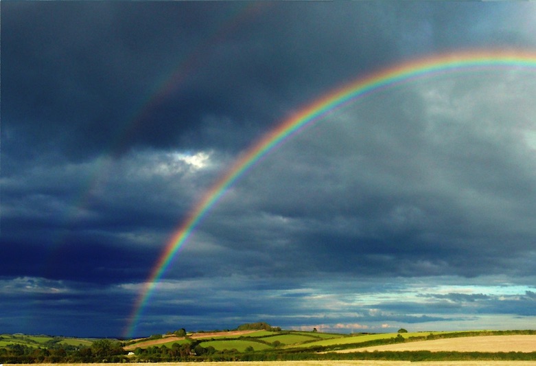 Foto van een donkere lucht met een regenboog
