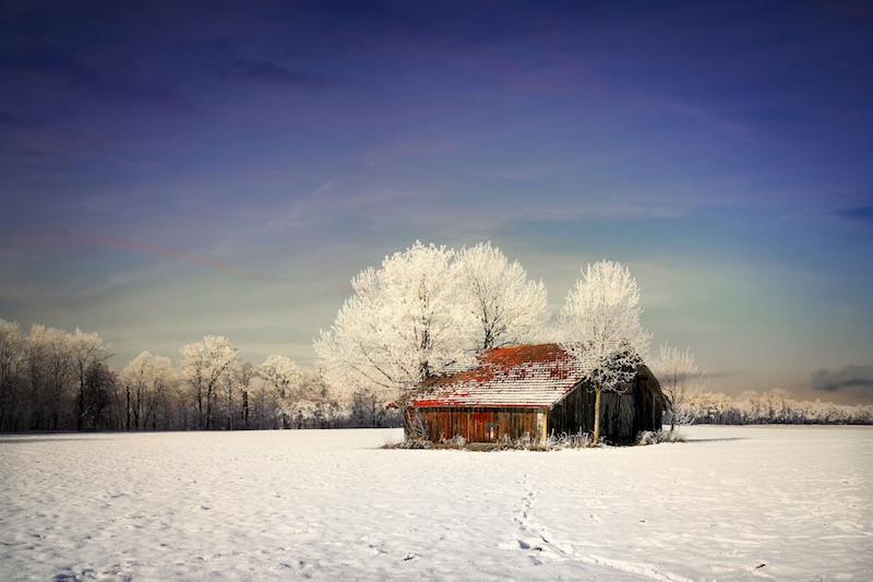 Foto van huisje in besneeuwd landschap