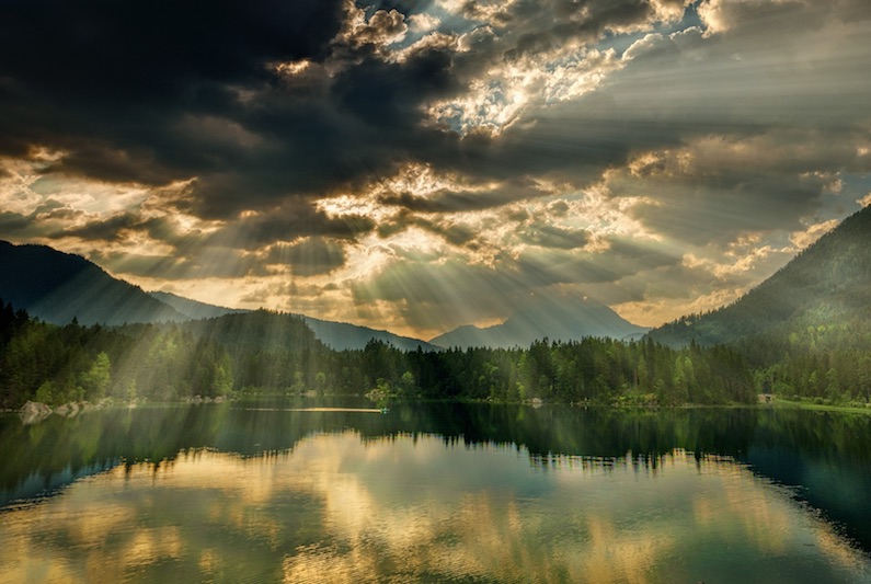 Foto van landschap met zonnestralen door wolk